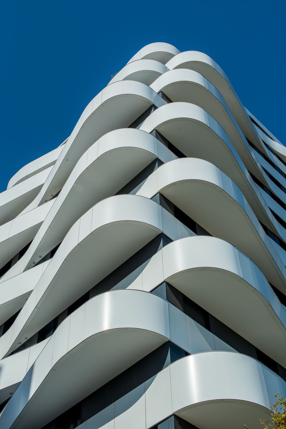 A curved modern apartment building against a blue sky